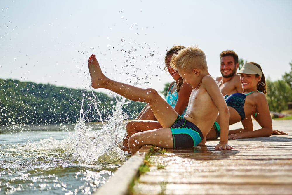 Famille au bord de l'eau avec un enfant qui éclabousse tout le monde santé famille