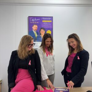 3 femmes autour dune plaquette, vêtue de rose avec le ruban octobre rose sur le coeur