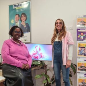 Deux femmes habillés en rose devant un ordinateur avec un ruban rose pour octobre rose
